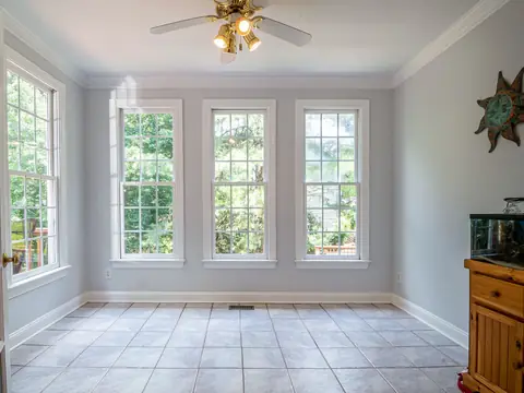 A bright, empty room with three tall windows letting in daylight