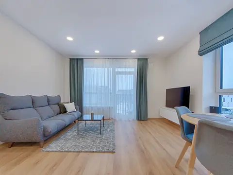 A tidy living room with a sofa and soft light from a balcony window