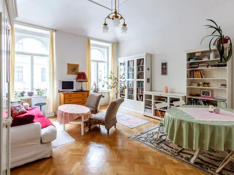 A bright, orderly living room with bookshelves, an armchair and tall windows